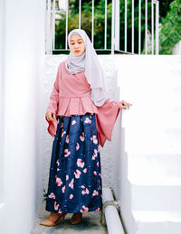 Portrait of smiling young woman standing against white wall