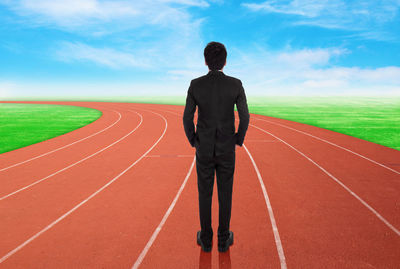 Rear view of man standing on field against sky