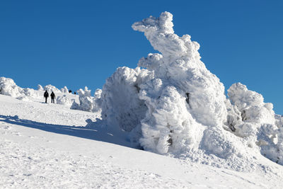 Snow covered land against clear blue sky