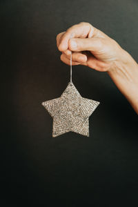 Cropped hand of woman holding star against black background