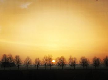 Silhouette trees on landscape against romantic sky at sunset