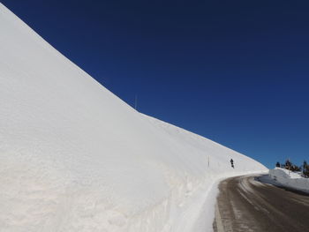 Snow covered landscape against clear blue sky