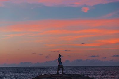 Man standing on beach against sky during sunset