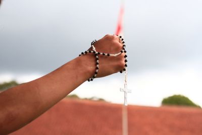 Close-up of hand holding prayer beads against flag