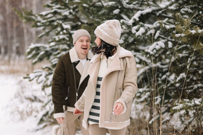 A man and a woman in love walk in a snowy forest among trees in the winter countryside in nature