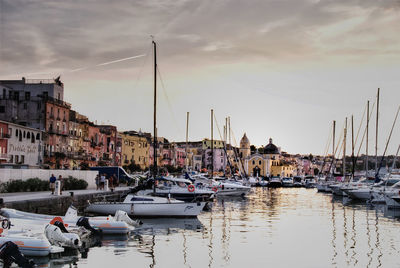 Sailboats moored at harbor against sky during sunset