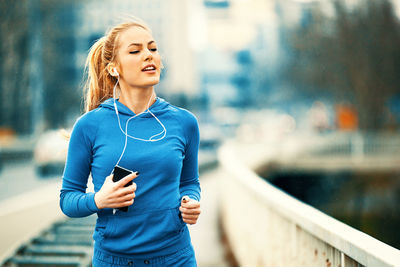 Young woman running on mobile phone in city