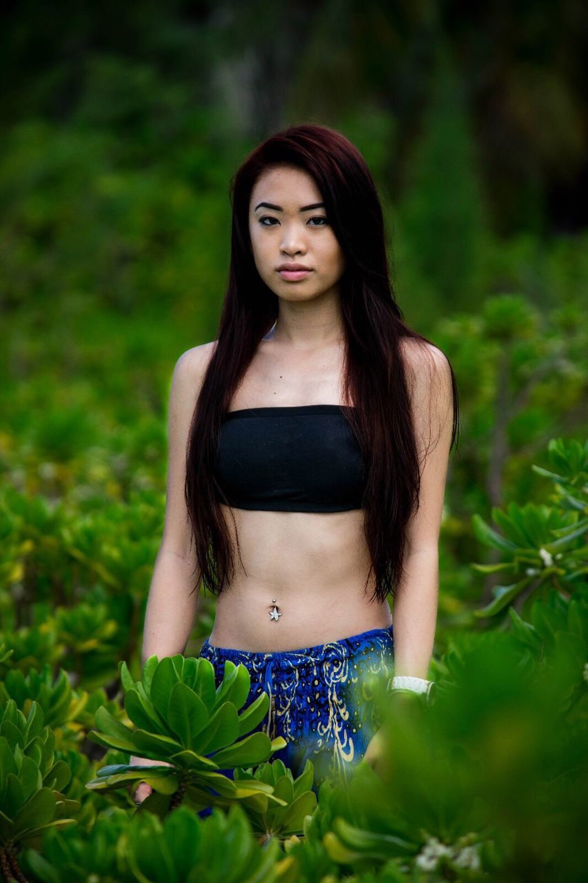 young adult, young women, person, long hair, portrait, front view, lifestyles, beauty, smiling, casual clothing, leisure activity, focus on foreground, fashion, femininity, black hair, confidence, sensuality, outdoors, plant, day, nature