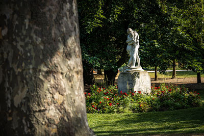 Statue of flowering plants against trees