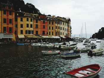 Sailboats moored on canal by buildings in city against sky