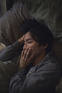 Sad man facing depression lying in bed