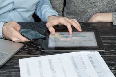 Midsection of man using mobile phone on table