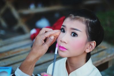 Cropped image of artist applying make-up on young woman