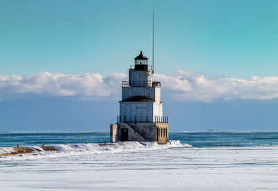 Lighthouse by sea against sky