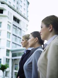 Young businesswoman with colleagues standing by building