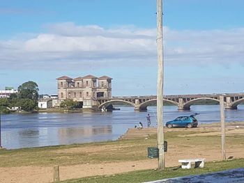 Built structure by river against sky