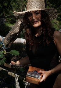 Midsection of woman holding hat while sitting outdoors