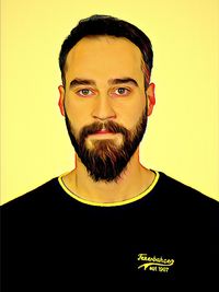 Portrait of young man standing against yellow background