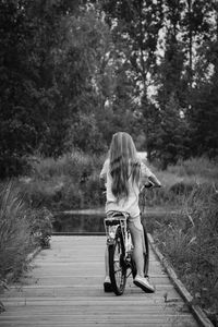 Rear view of girl with bicycle on boardwalk