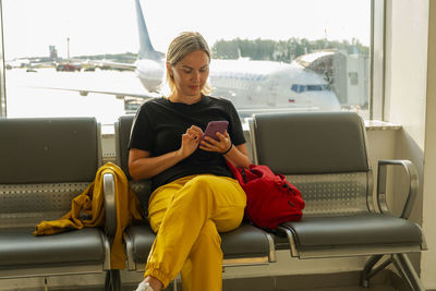 Young woman using phone while sitting on sofa at home