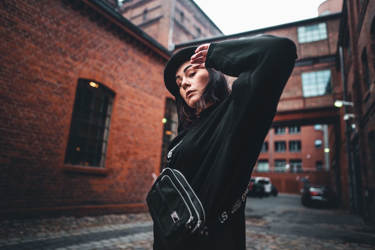 LOW SECTION OF WOMAN STANDING BY BUILDING IN CITY