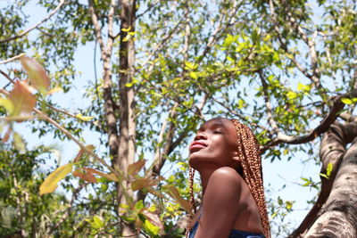 Low angle portrait of woman against tree