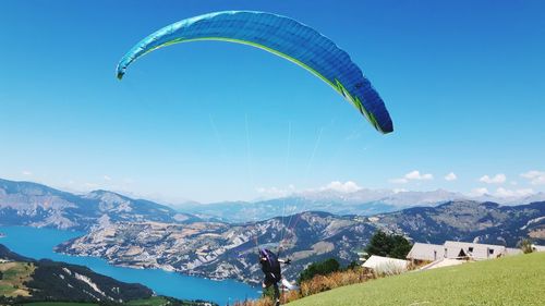 Rear view of person paragliding by mountains against sky