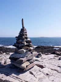 Stack of rocks on beach against clear sky