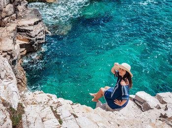 High angle view of woman on rock by sea