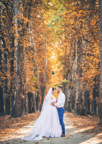 Rear view of couple standing in forest during autumn