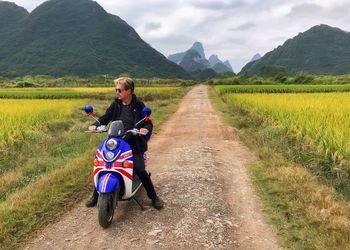 Man riding motorcycle sitting on field against sky