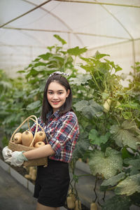 Portrait of smiling young woman standing against plants