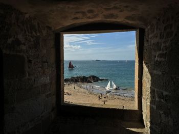 Sea against sky seen through window