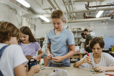 Group of male and female students working with electrical components in robotics class