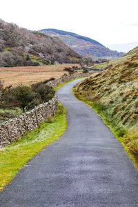 Road leading towards mountain against sky