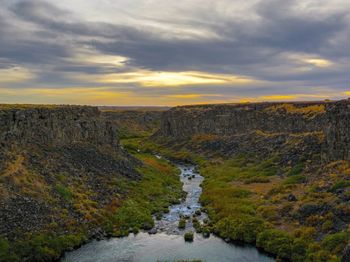 Scenic view of waterfall against sky during sunset