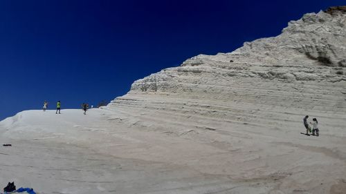 People on mountain road against clear sky