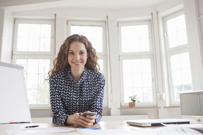 Portrait of smiling woman at desk in office