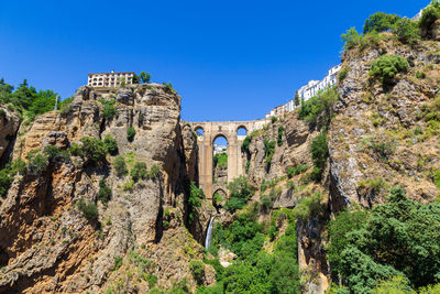 Plants growing on rocks against clear blue sky