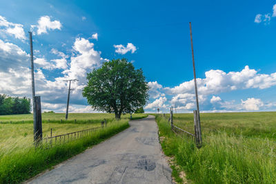 Road amidst field against sky