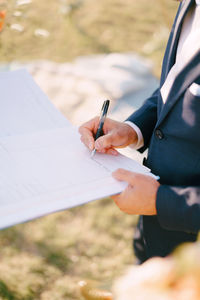 Midsection of woman writing in book