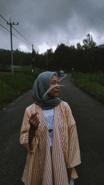 Girl standing on road against sky.