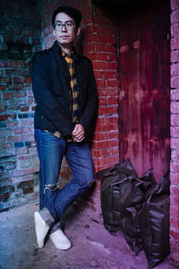 Portrait of young man standing against wall