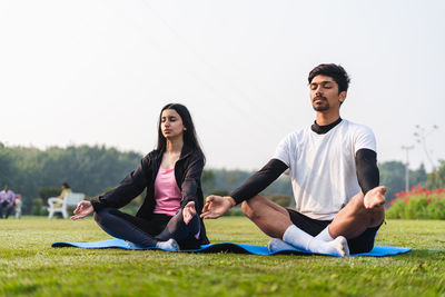 Young couple doing yoga and meditating in the park early in the morning. healthy lifestyle concept.