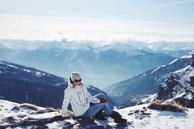 People sitting on snowcapped mountain against sky