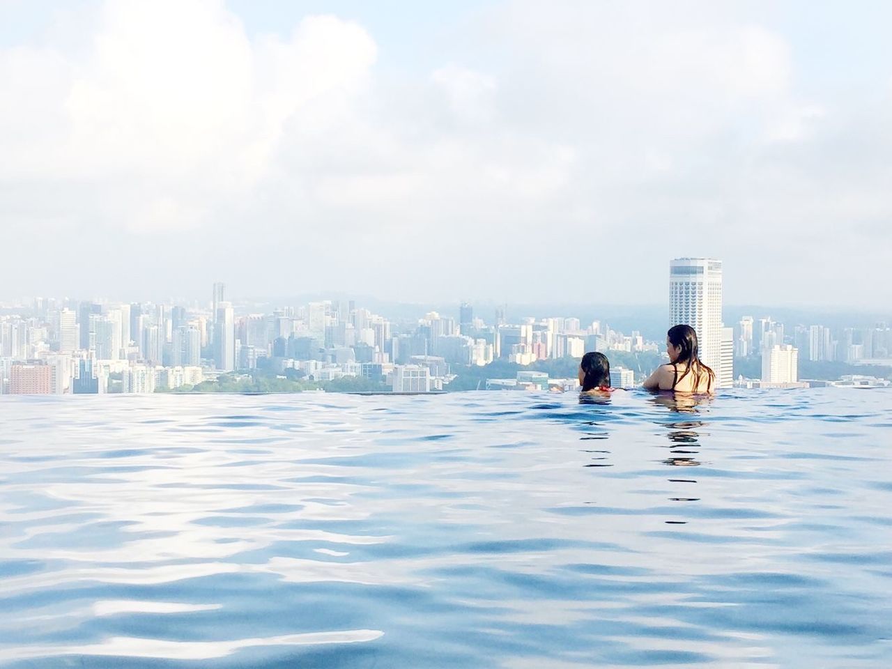 water, building exterior, architecture, built structure, city, sky, lifestyles, leisure activity, men, waterfront, cityscape, cloud - sky, sea, person, city life, skyscraper, urban skyline