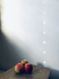 Close-up of apples on table against wall