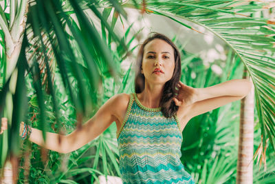 Portrait of young woman standing by trees