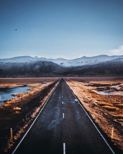 Road leading towards mountains against sky