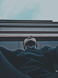 Low angle view of man sitting on window